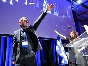 Quebec Conservative Leader Éric Duhaime, left, waves to delegates at the end of his opening speech of the party's congress on Saturday, Nov. 18, 2023, in Lévis. Former party candidate Anne Casabonne, right, raises her hand.