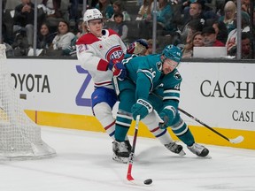 San Jose Sharks' Tomas Hertl, right, reaches for the puck in front of Canadiens defenceman Kaiden Guhle (21)