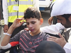 Twelve-year-old Amr Jandieh, who was wounded in the Israel-Hamas war, gestures, while surrounded by Emirati officials as he is brought down from the plane to an ambulance in Abu Dhabi, United Arab Emirates, Saturday, Nov. 18, 2023.