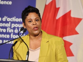 Marci Ien speaks at a podium with a Canadian flag behind her