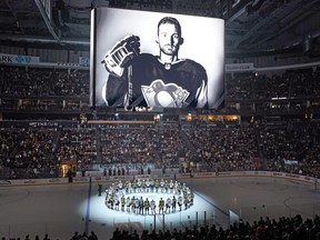 The Penguins and Ducks gathered at centre ice before a game in Pittsburgh on Mon., Oct. 30, to honour former Penguin player Adam Johnson, shown on the scoreboard, who died while playing in an English hockey league game.