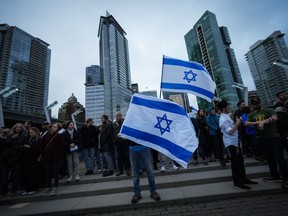 People hold Israeli flags during a vigil organized by the Jewish Federation of Greater Vancouver.