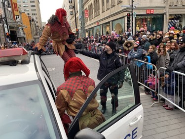 Christmas elves have a look at a Montreal police car at the 71st Santa Claus parade on Saturday, Nov. 25, 2023.