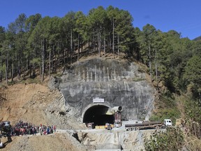 People watch rescue and relief operations at the site of an under-construction road tunnel that collapsed in India.