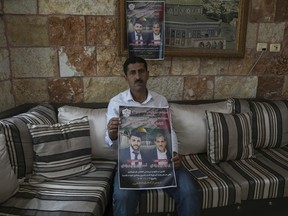 Abdelazim Wadi, 50, holds up a poster commemorating his brother, Ibrahim Wadi, and his nephew, Ahmed Wadi.