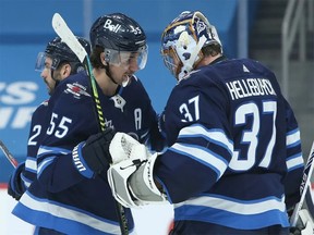 Winnipeg Jets centre Mark Scheifele (left) and goaltender Connor Hellebuyck celebrate a win over the Montreal Canadiens.