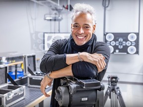 A man grins while resting his arms on movie equipment.