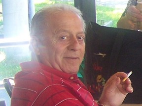 An older man in a red striped shirt turns toward the camera. He's holding a cigarette.