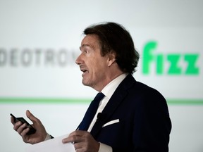 Pierre Karl Péladeau, with a smartphone in hand, speaks with the Videotron and Fizz logos visible beside him