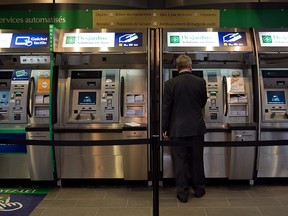 A man interacts with one of several Desjardins-branded ATMs