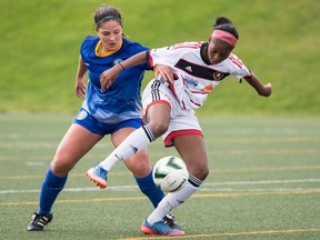 Two women on opposing teams vie for the ball during a soccer game