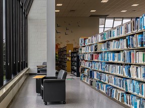 Seats facing windows in front of rows of books at a library.