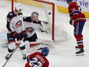 Canadiens' Cole Caufield scores overtime wiiner over Blue Jackets goaltender Elvis Merzlikins, while Canadiens' Nick Suzuki and Blue Jackets' Jack Roslovic look at the play on Oct. 26, 2023.