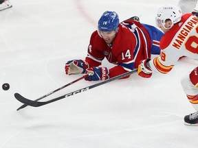 Canadiens' Nick Suzuki dives in an effort to get to the puck before Flames' Andrew Mangiapane during game last month at the Bell Centre.