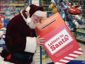 Santa Claus peers into a red box marked: Letters to Santa