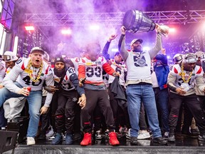 Alouettes' Kristian Matte raises the Grey Cup while he and his teammates celebrate with fans after theri parade in Montreal on Nov. 22.