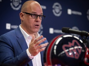 Mark Weightman speaks at a news conference behind an Alouettes helmet on a table