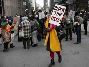 A person holds a sign that reads 'Block the hike!' on a protest on a downtown street