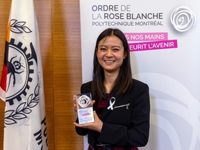 A young woman holds an award in front of a sign reading Ordre de la Rose Blanche.