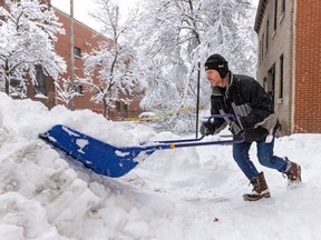 A man shovels snow with big blue shovel