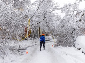 man walking on snow covered street fallen branches