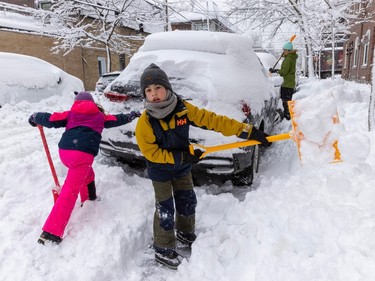 Two children shovel slow from around a parked car