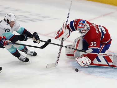 The puck is just in front of the Canadiens goaltender as a Kraken player skates in