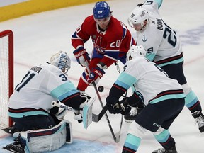 Canadiens' Juraj Slafkovsky tries to bat puck out of the air while surrounded by Kraken goaltender Philipp Grubauer, Vince Dunn and Adam Larsson.