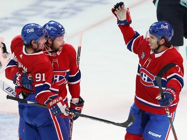 Three Canadiens players skate toward each other for a hug
