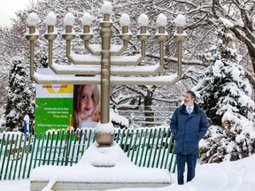 Hampstead Mayor Jeremy Levi stands next to a giant menorah outdoors in the snow.