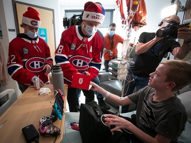 A young boy is handed an object by Mike Matheson, wearing a Canadiens jersey, tuque and mask