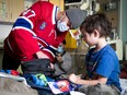 Jayden Struble bends over to handle an object next to a young boy in a hospital bed