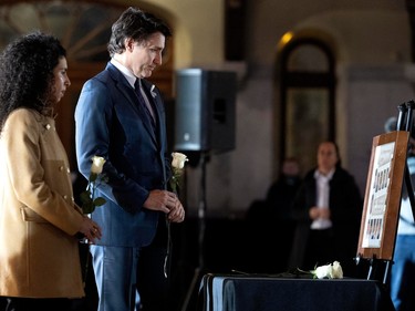 Justin Trudeau prepares to place a white rose before a photo montage