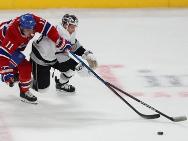 A Canadiens and Kings player reach for the puck ahead of them