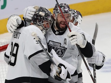 Two Kings players embrace their goaltender