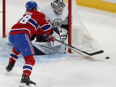The puck is just behind the red line next to the Kings goal and a Montreal player extends his stick trying to reach it