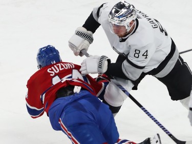 Canadiens' Nick Suzuki falls to the ice underneath a Kings player