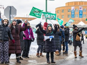 People holding green 'NOUS' union flags cheer outside with the Lakeshore General Hospital in the background