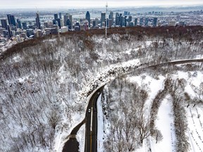 An aerial view of snowy Camillien-Houde Way on Mount Royal, with the downtown Montreal skyline in the background.