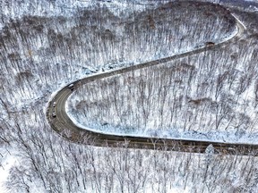 Aerial view of a road snaking over a snowy hill.