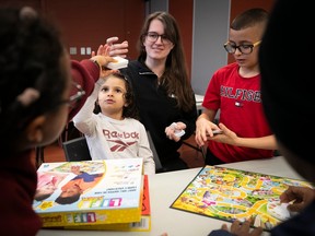 A woman watches as young children play with a board game