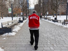 A man is seen from behind on a wide path. His red jacket says "McGill" on the back.