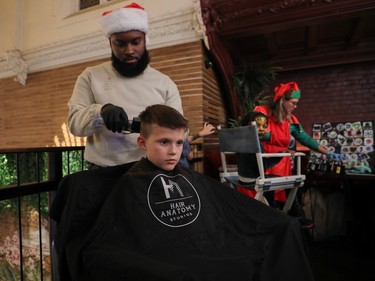 Hugo Lepine gets his hair cut by Chris Montina at an event called One Magic Moment in Montreal on Sunday, Dec. 17, 2023.