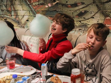Abby Bavota holds cotton candy for a friend as Jacob Potter digs into some food at a special holiday event called One Magic Moment in Montreal on Sunday, Dec. 17, 2023.