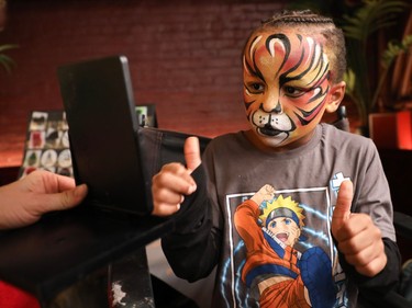 Aidan Bouchard approves of his face painting done by Nathalie Legault at an event called One Magic Moment in Montreal on Sunday, Dec. 17, 2023.