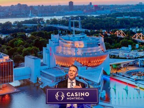 A man speaks at a podium with a projection of a casino and skyline behind him.