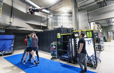 Porter Harley McLeish, right, watches as acrobat Mathieu Campan is thrown in the air during backstage rehearsals for the new Cirque du Soleil ice show Crystal at the Bell Centre in Montreal on Thursday, Dec. 21, 2023.