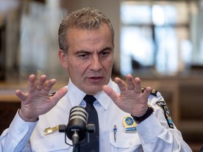 Montreal police chief Fady Dagher is gesturing with his hands up, in front of a microphone.
