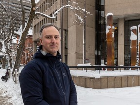 Portrait of a man standing outside in winter, next to a downtown building.