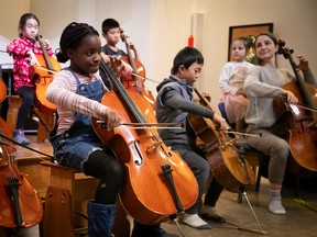 Children perform with cellos on a platform.